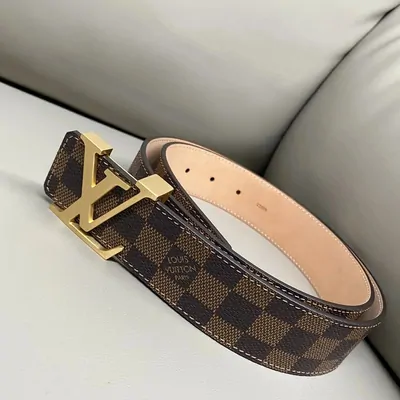 A brown checked canvas belt with a gold square buckle, coiled on a cream leather seat