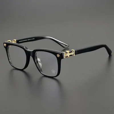 Black rectangular spectacle frames with clear lenses and a small metal detail on the temple, photographed on a grey surface
