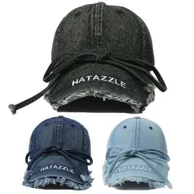 Three distressed denim baseball caps on white, one charcoal above two in lighter blue washes, each with a frayed brim and an embroidered word across the front